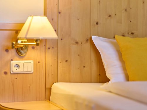 Nähe Bett mit gelbem Kissen Holzwand Lampe und Steckdose auf Nachttisch