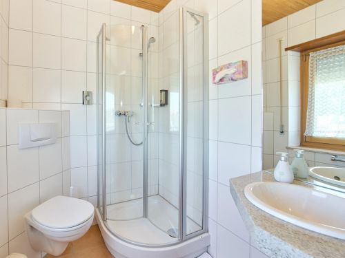 Helles Badezimmer mit Dusche Toilette Fenster und Waschbecken mit Spiegel und Seifenspendern