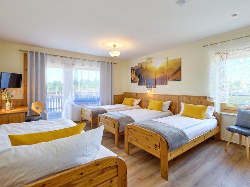 Hell eingerichtetes zimmer mit drei holzbetten gelbe kissen wandbild und fenster mit gardinen im hintergrund