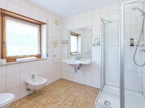 Helles modernes badezimmer mit fenster großer spiegel duschkabine waschbecken und bidet braune bodenfliesen