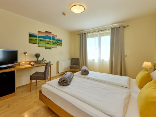 Modern eingerichtetes Hotelzimmer mit zwei betten fernseher und fenster mit vorhängen
