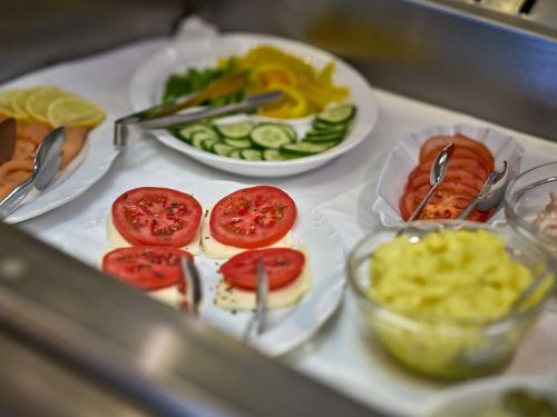 Verschiedene Frische Salate mit Tomaten Gurken und Kartoffelsalat auf weißen Tellern mit Besteck