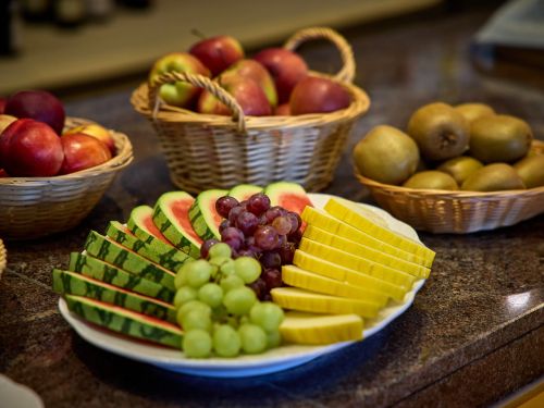 Obstkorb mit Äpfeln Kiwis und Teller mit Wassermelone Trauben und geschnittenem Kürbis auf Granittheke