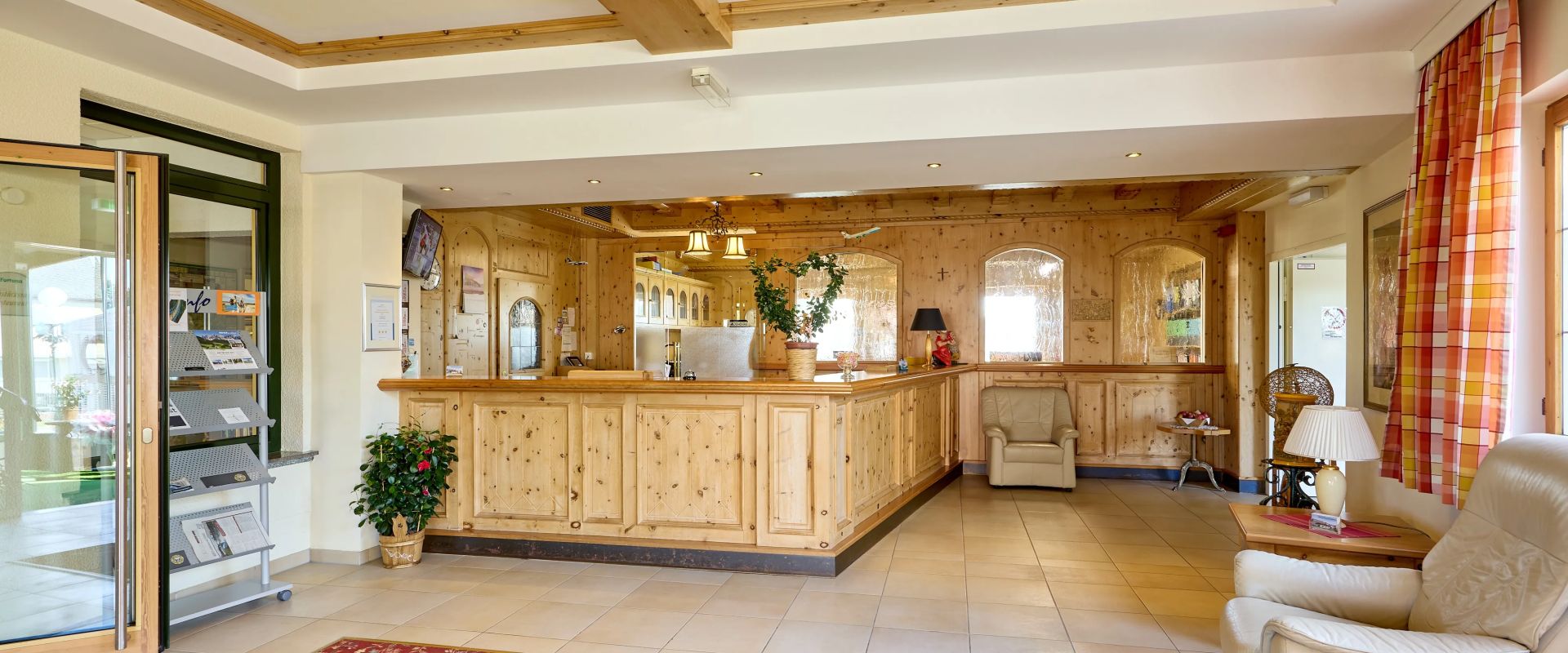 Helle hotel lobby mit holztheke roten teppich und beigen sesseln vor fenster mit bunten gardinen